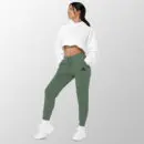 Woman in Alpine Green AddyMiRi joggers with a white cropped hoodie, embroidered mark on the left thigh.