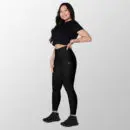 Woman wearing black high-rise leggings, side view, with a hand in the side pocket.