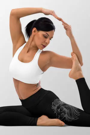 Woman performing a yoga pose in black leggings with line drawing of a lions head